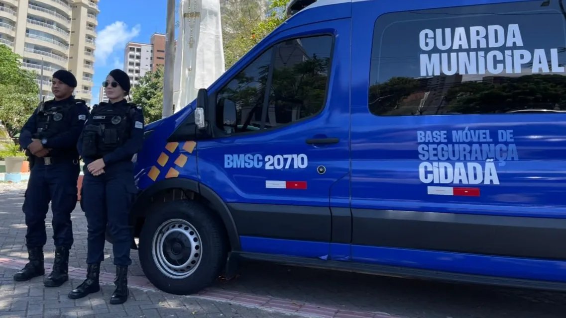 duas guardas municipais posam na frente de uma van do órgão